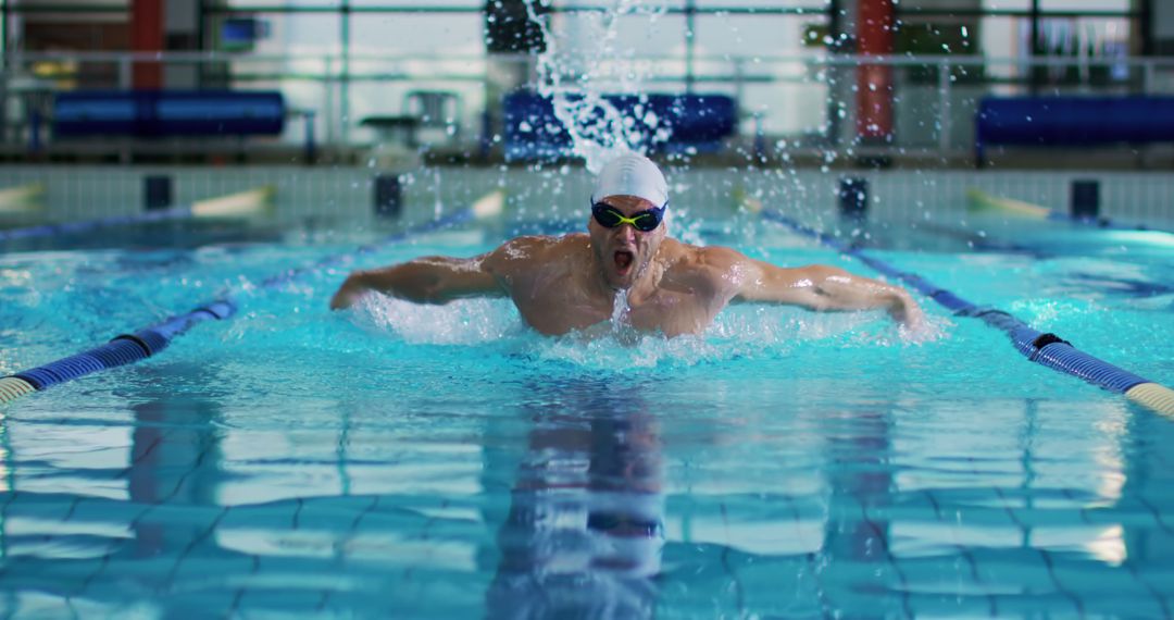 Professional Swimmer Performing Butterfly Stroke in Indoor Pool - Free Images, Stock Photos and Pictures on Pikwizard.com