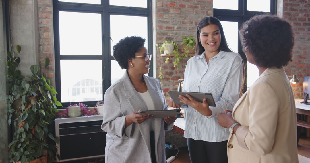 Diverse Female Team Discussing Work with Technology in Modern Office