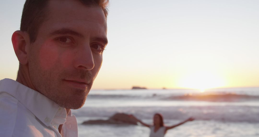 Man enjoying beach at sunset with woman in background - Free Images, Stock Photos and Pictures on Pikwizard.com