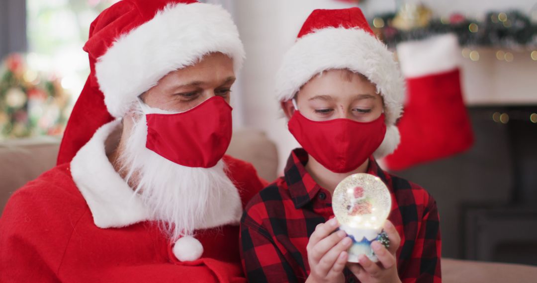 Father and Son in Santa Hats Wearing Masks with Christmas Snow Globe - Free Images, Stock Photos and Pictures on Pikwizard.com