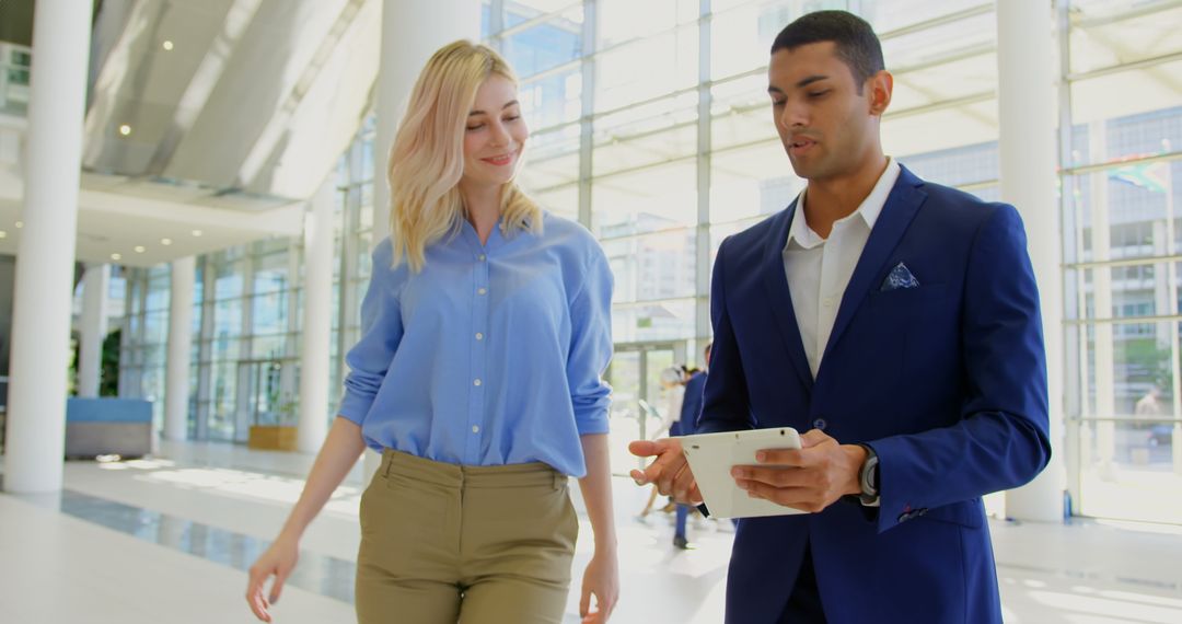 Business Professionals Collaborating on Digital Tablet in Modern Lobby