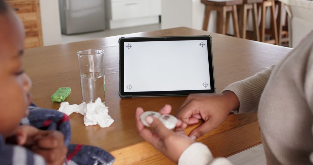 Mother Caring for Sick Child with Digital Thermometer and Tablet