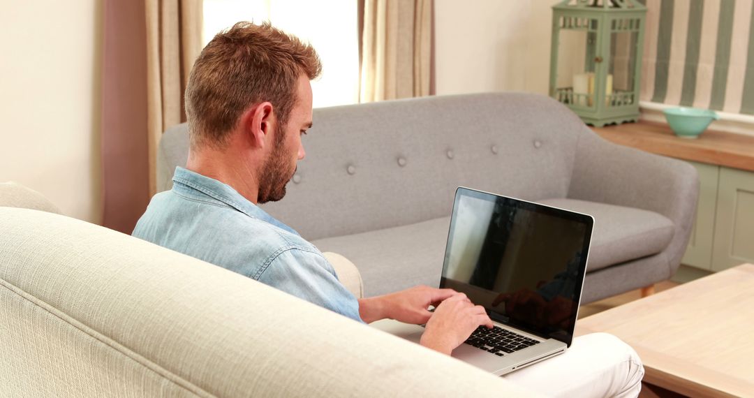 Man Working on Laptop from Ribbed Couch in Cozy Living Room - Free Images, Stock Photos and Pictures on Pikwizard.com