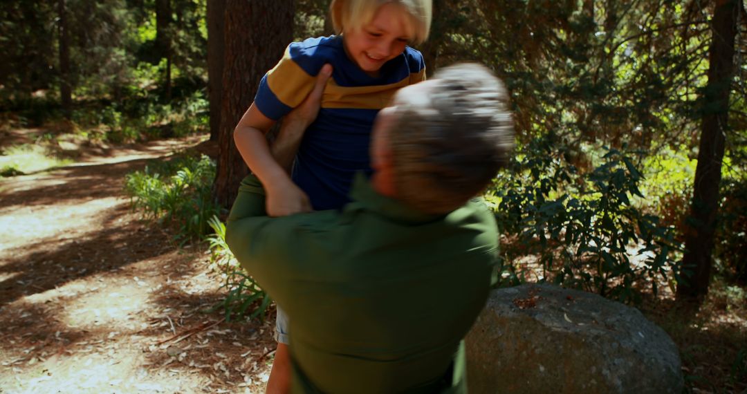 Joyful Moment of Elderly Man Lifting Young Boy in Forest - Free Images, Stock Photos and Pictures on Pikwizard.com