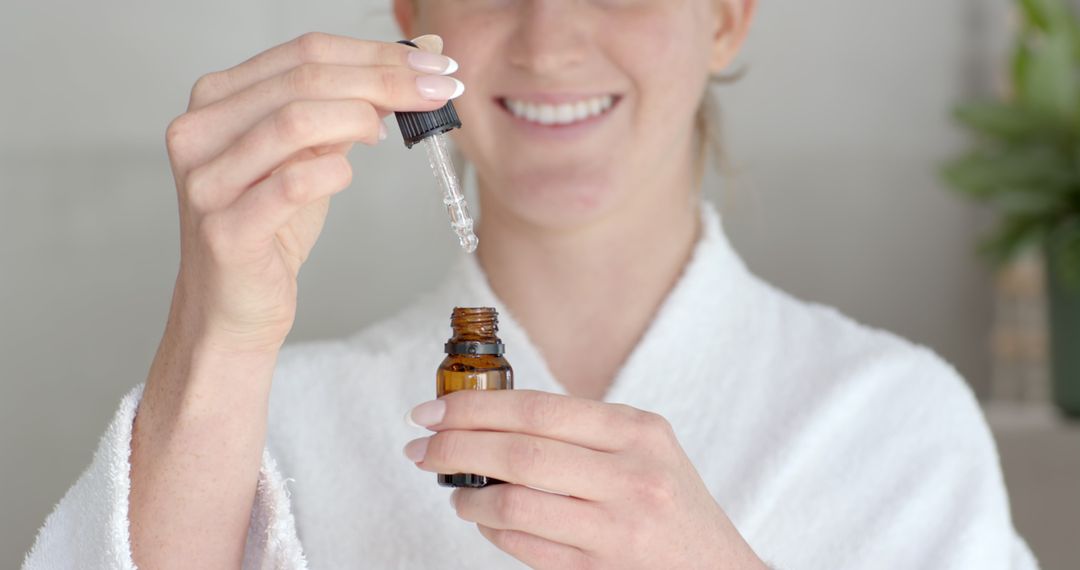 White Female in Bathrobe Using Serum Dropper for Skincare Routine