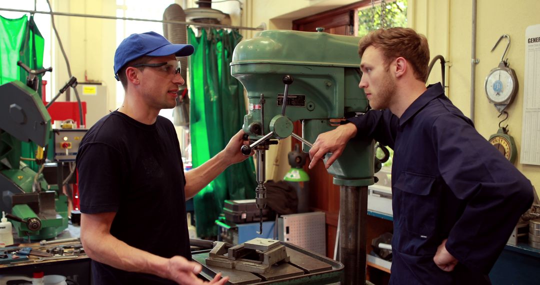 Two technicians discussing work next to industrial drilling machine - Free Images, Stock Photos and Pictures on Pikwizard.com