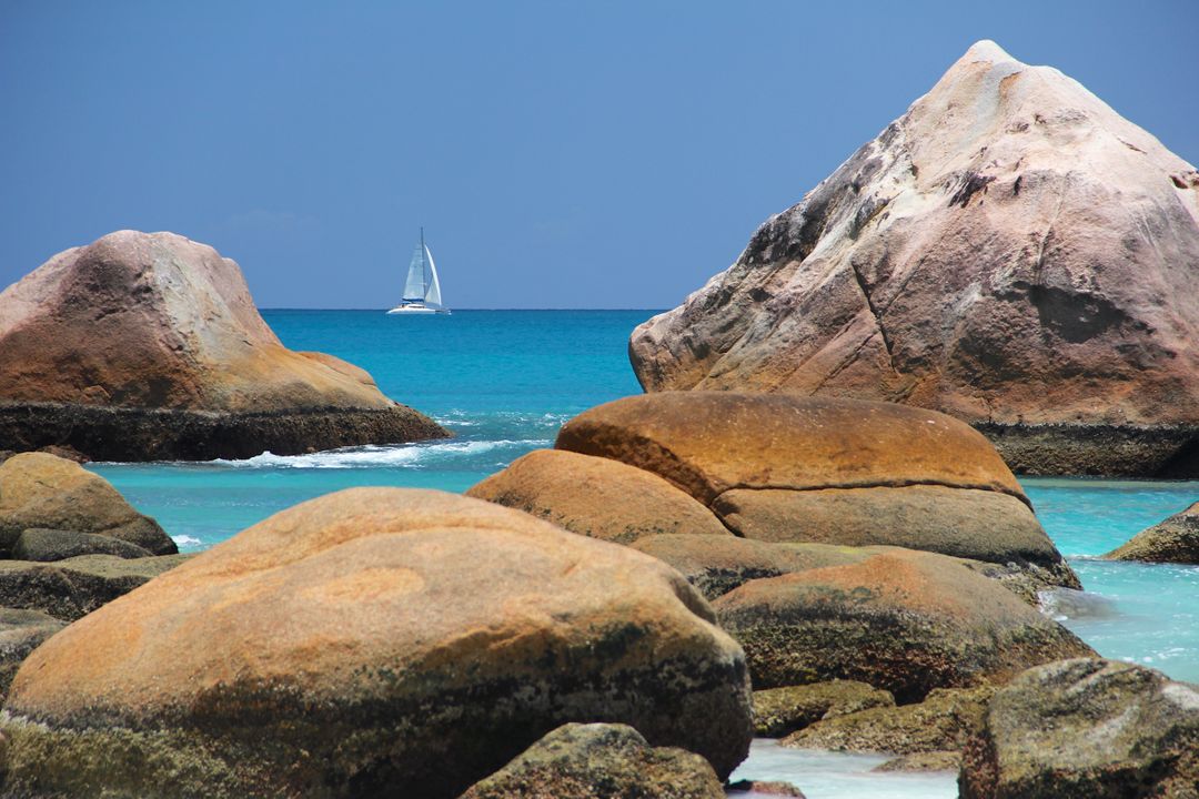 Sailboat Navigating Between Rocky Islands in Pristine Blue Waters - Free Images, Stock Photos and Pictures on Pikwizard.com