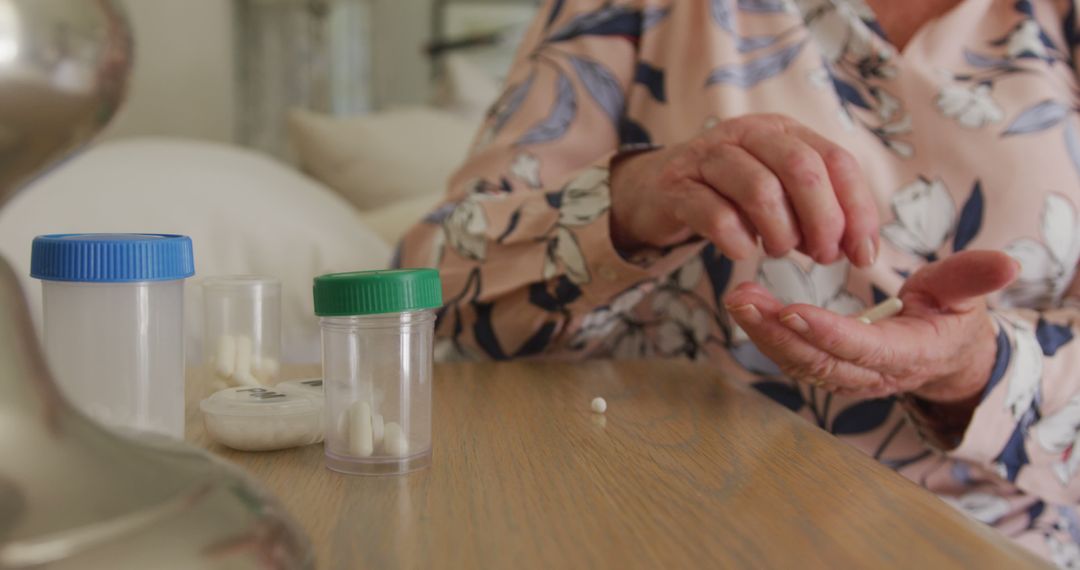 Mid section of caucasian senior woman removing pills from medicinal containers at home - Free Images, Stock Photos and Pictures on Pikwizard.com