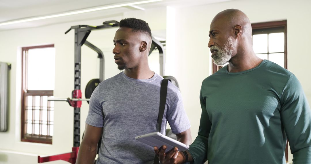Athletic Men Analyzing Fitness Data in Modern Gym