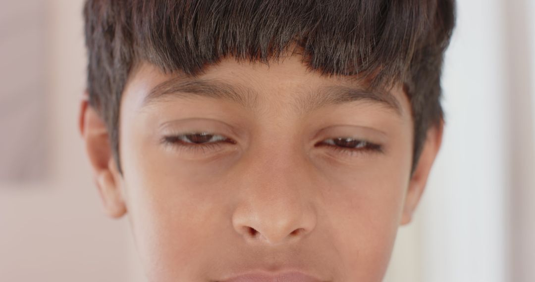 Boy with Calm Expression Standing in Diffused Light Indoors