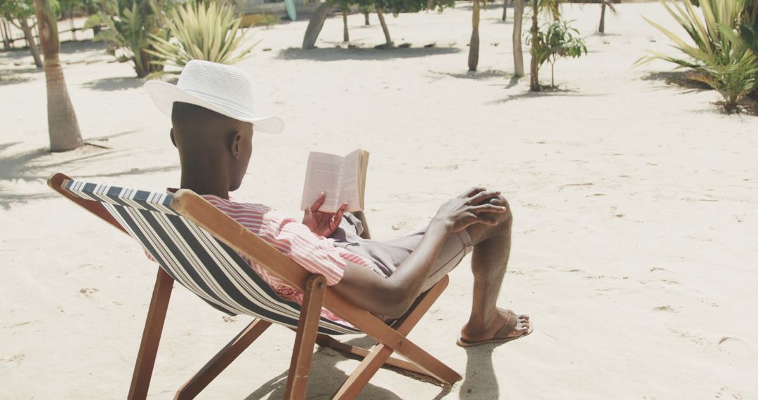 Man Relaxing on Sunny Beach in Deck Chair Reading Book - Free Images, Stock Photos and Pictures on Pikwizard.com