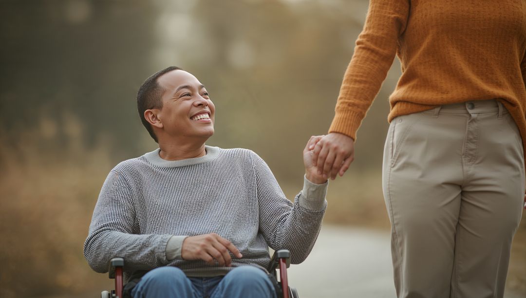 Man in Wheelchair Smiling at Companion on Autumn Pathway