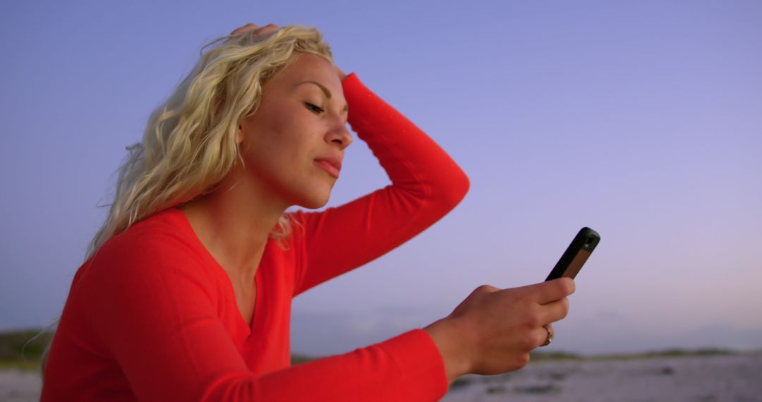 Woman Relaxing on Beach with Mobile Phone at Dusk