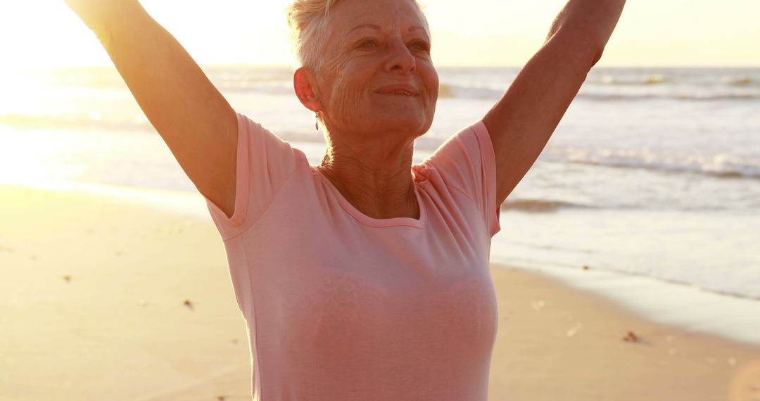 Senior Woman Enjoying Sunset on Beach with Arms Raised - Free Images, Stock Photos and Pictures on Pikwizard.com