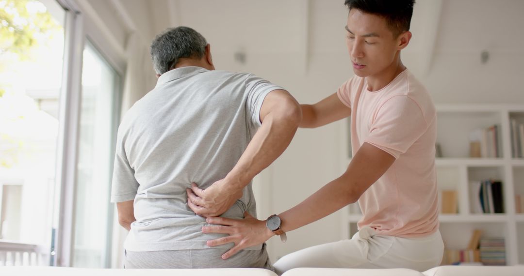 Physiotherapist Assisting Senior Man with Back Pain