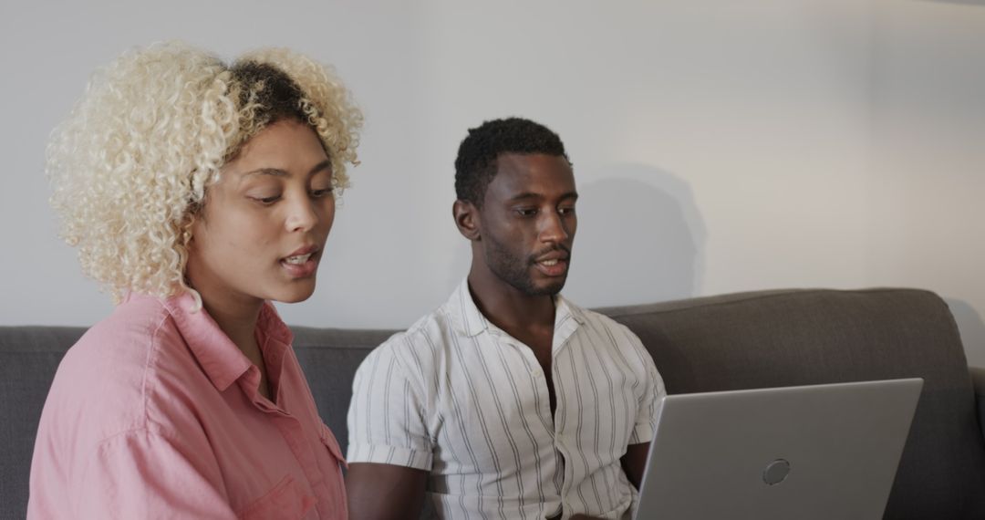 Couple Relaxing on Sofa Sharing Laptop Experience