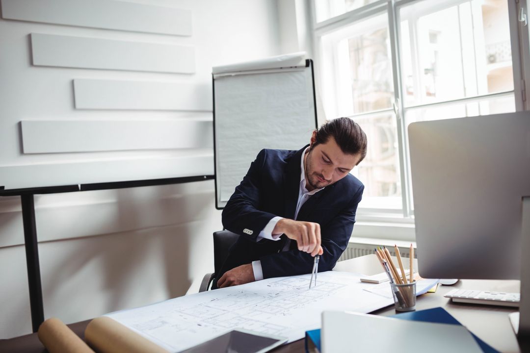 Architect Measuring Blueprints Using Compass Office Environment