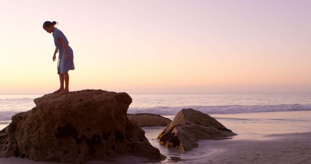 Woman Enjoying Sunset on Rock by Sea - Free Images, Stock Photos and Pictures on Pikwizard.com