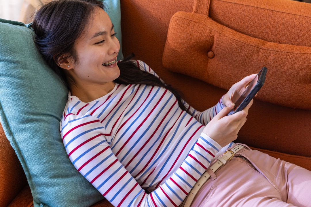 Young Woman Relaxing on Couch Using Smartphone at Home