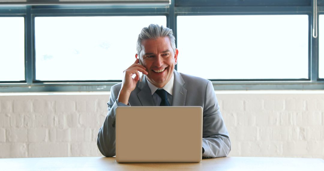 Smiling Businessman Working on Laptop at Office Desk - Free Images, Stock Photos and Pictures on Pikwizard.com