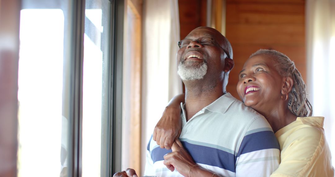 Joyful Senior African American Couple Hugging by Window
