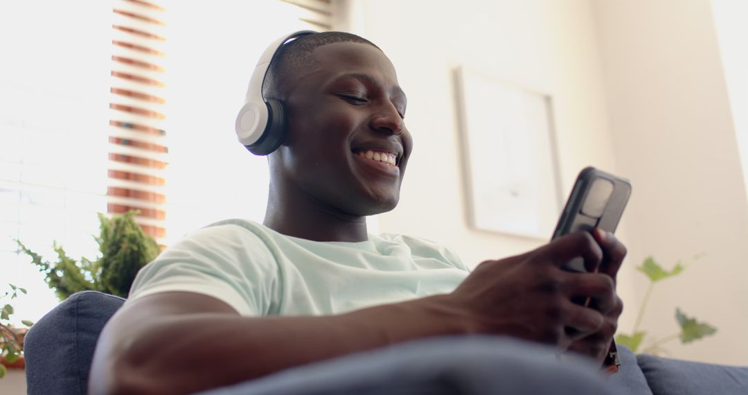 Smiling Man Relaxing with Smartphone and Headphones Indoors