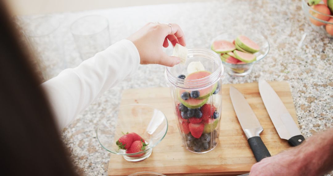 Couple Preparing Fresh Fruit Smoothie in Sunny Kitchen
