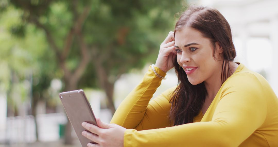 Young Woman Smiling While Watching Tablet Outdoors - Free Images, Stock Photos and Pictures on Pikwizard.com