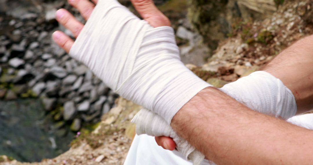 Close-Up of Hands Wrapping Gauze Bandage Outdoors Near Rocky Shore - Free Images, Stock Photos and Pictures on Pikwizard.com