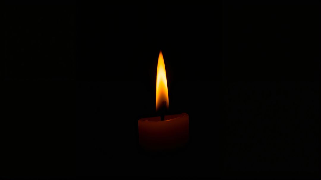 Single Pillar Candle Burning with Warm Flame and Soft Halo on Dark Minimalist Background