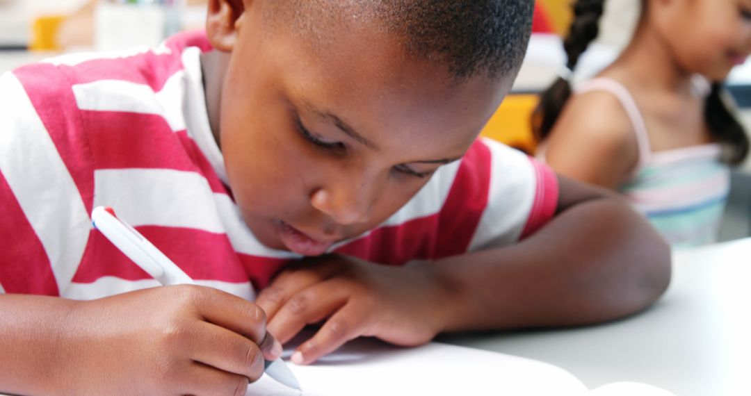 Young Boy Studying Diligently at Desk, Engaging in Classroom Education - Free Images, Stock Photos and Pictures on Pikwizard.com