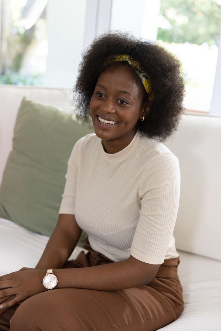 Smiling Woman Relaxing on Sofa Enjoying Peaceful Moment at Home