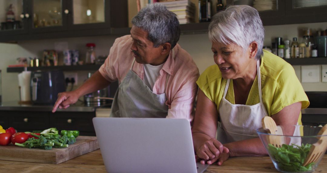 Senior Couple Cooking Together at Home Using Laptop