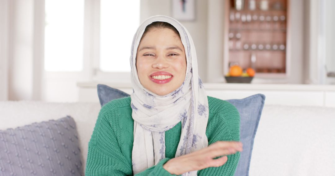 Smiling Woman in Hijab Sitting on Comfortable Sofa at Home - Free Images, Stock Photos and Pictures on Pikwizard.com