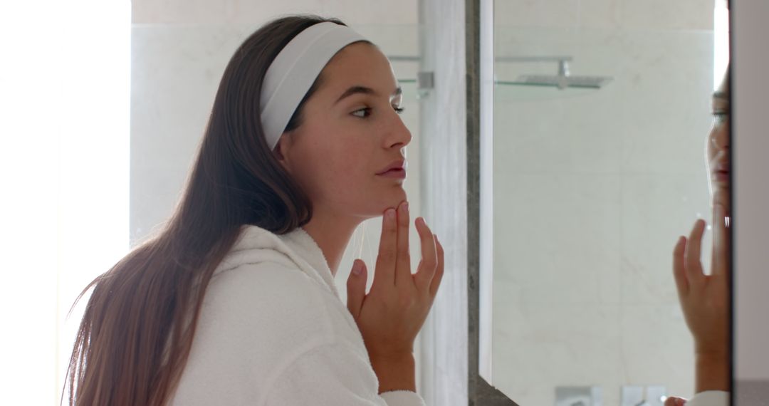 Woman Touching Chin While Admiring Self in Bathroom Mirror