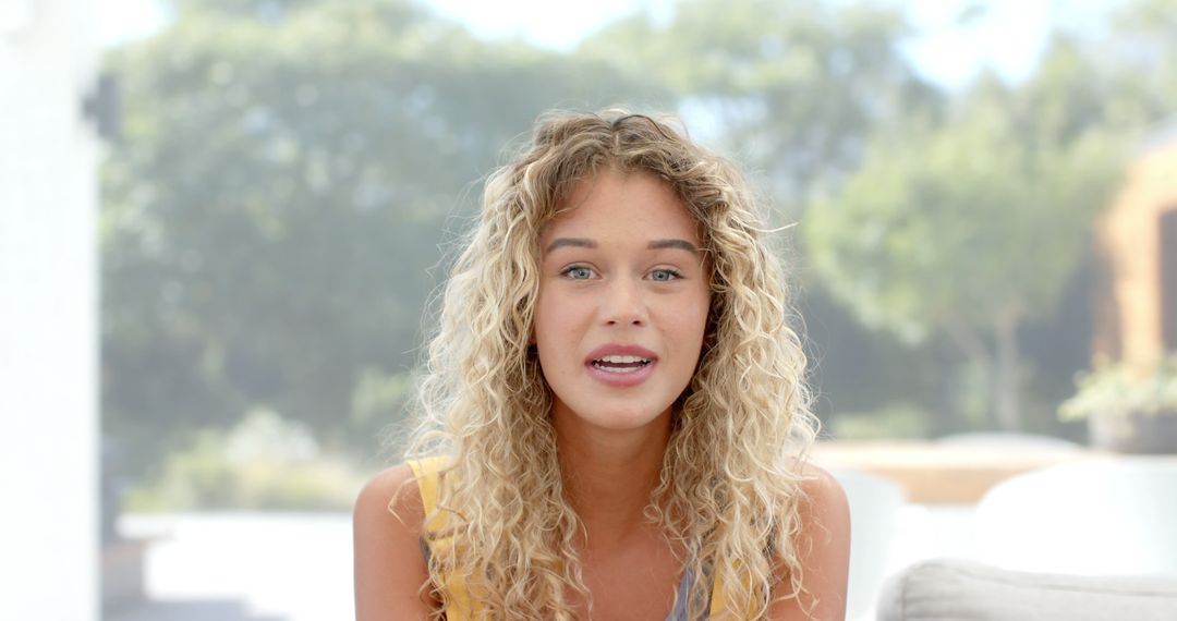 Smiling young woman with curly blond hair enjoying outdoors - Free Images, Stock Photos and Pictures on Pikwizard.com