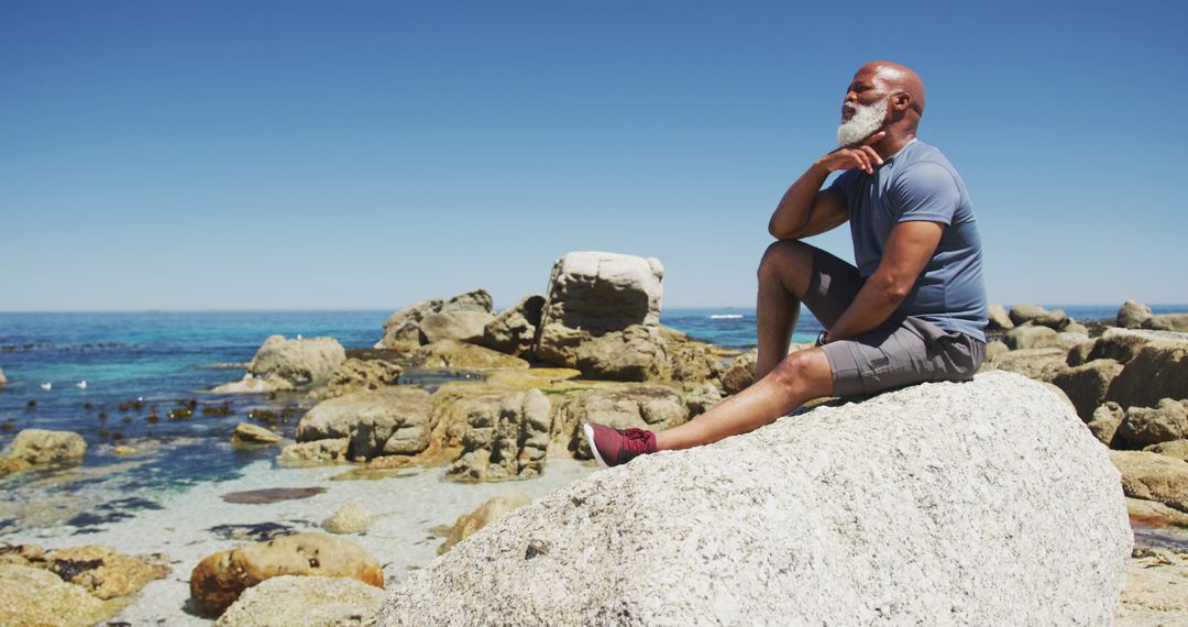 Mature Man Relaxing on Rock by Ocean, Enjoying Scenic View - Free Images, Stock Photos and Pictures on Pikwizard.com