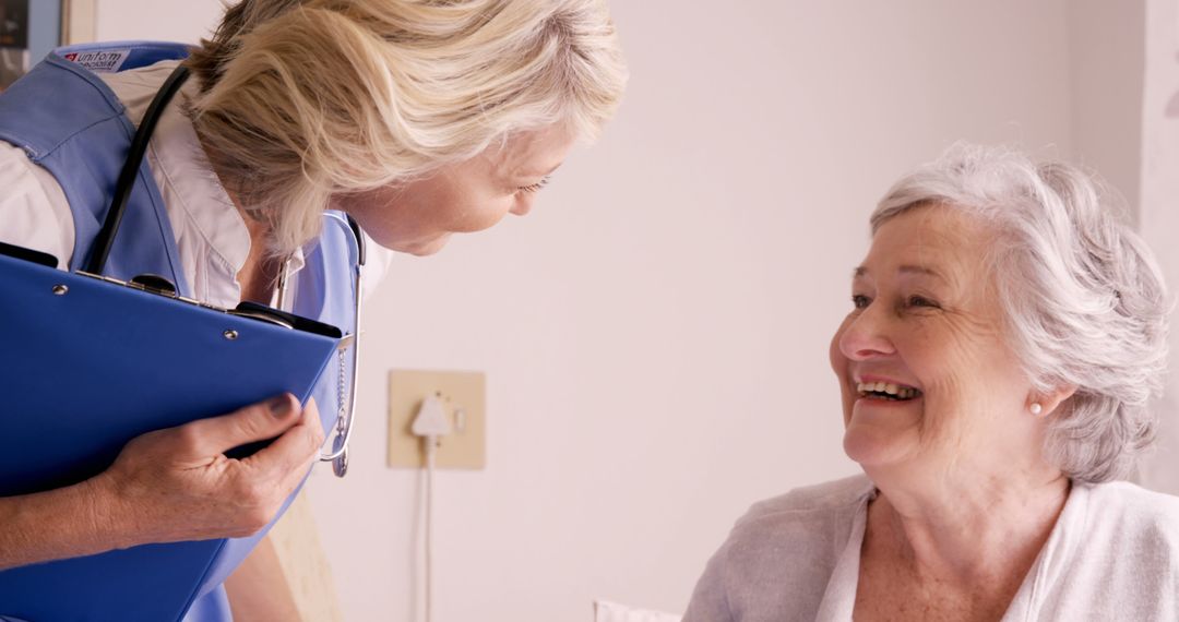 Elderly Woman Smiling with Caregiver Holding Medical Chart - Free Images, Stock Photos and Pictures on Pikwizard.com