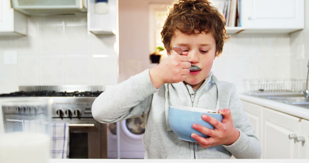 Child Eating Breakfast Cereal in Modern Kitchen - Free Images, Stock Photos and Pictures on Pikwizard.com