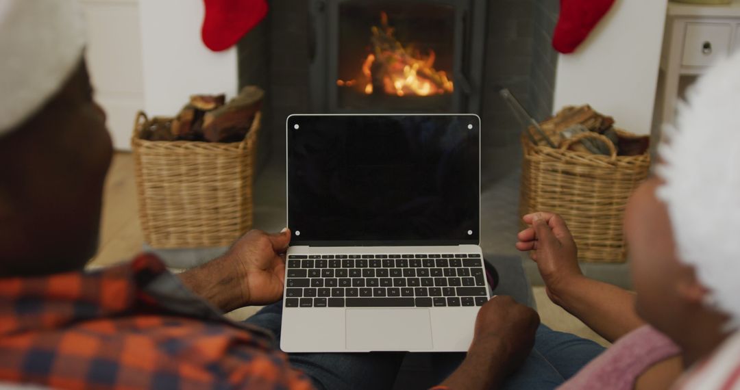 Couple using laptop by fireplace during Christmas holidays - Free Images, Stock Photos and Pictures on Pikwizard.com