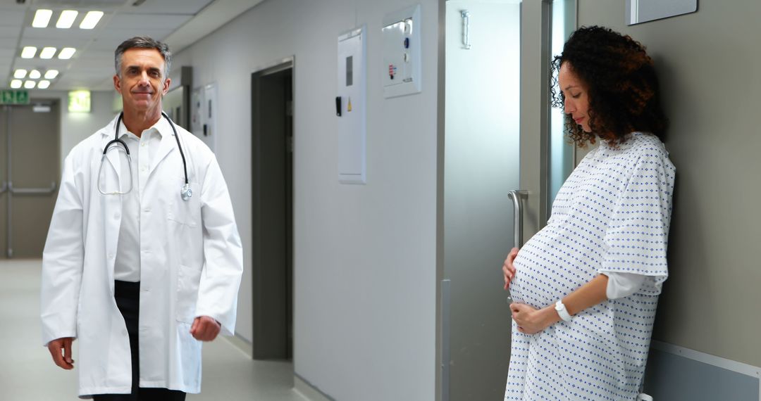 Pregnant Woman in Hospital Corridor with Doctor Approaching - Free Images, Stock Photos and Pictures on Pikwizard.com