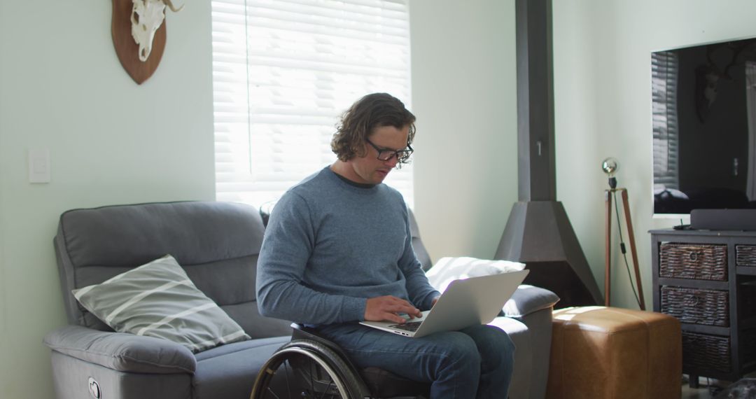 Young Man in Wheelchair Using Laptop in Living Room - Free Images, Stock Photos and Pictures on Pikwizard.com