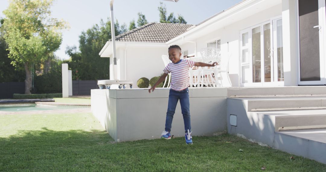 Young Boy Jumping Outdoors in Modern Backyard - Free Images, Stock Photos and Pictures on Pikwizard.com