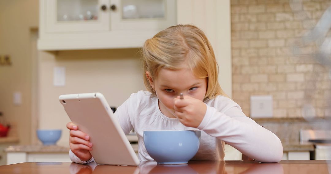 Young Girl at Home Eating Breakfast While Using Digital Tablet - Free Images, Stock Photos and Pictures on Pikwizard.com