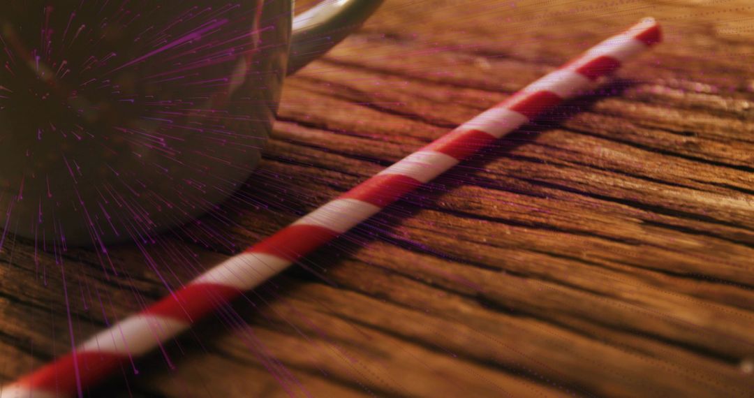 Red White Striped Paper Straw Lying Diagonally on Weathered Wood with Ceramic Mug and Purple Flare