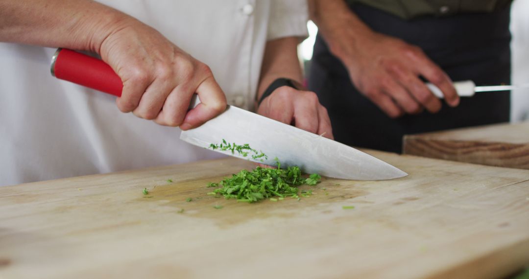 Chef chopping fresh herbs with sharp knife on wooden cutting board - Free Images, Stock Photos and Pictures on Pikwizard.com