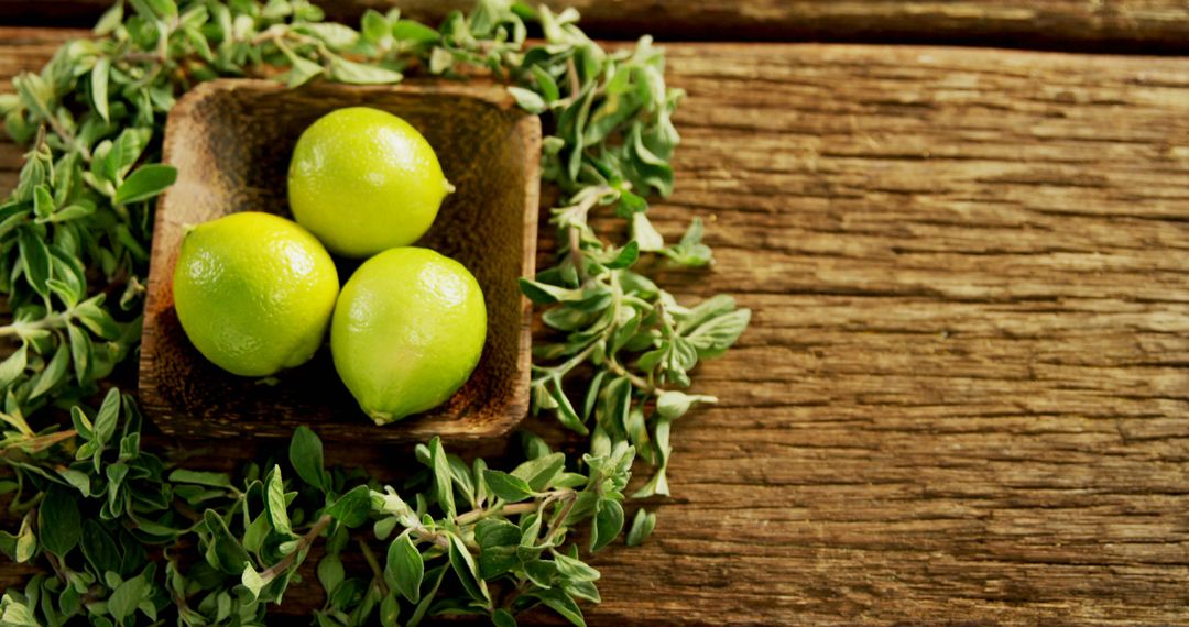 Fresh Limes in Wooden Bowl with Green Herbs on Rustic Wooden Surface - Free Images, Stock Photos and Pictures on Pikwizard.com