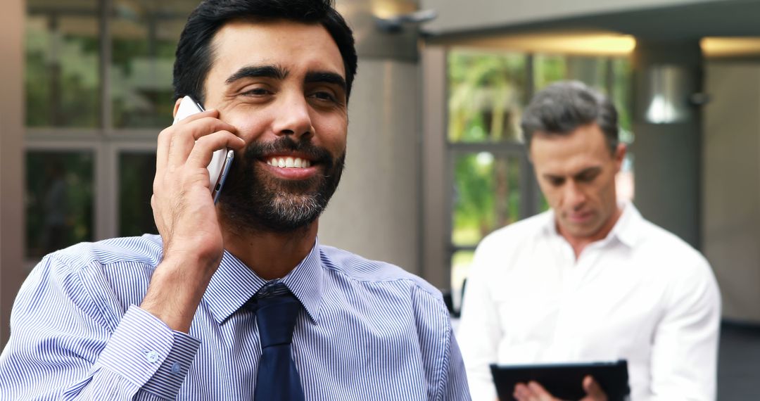 Smiling Businessman Taking Call in Modern Office Environment - Free Images, Stock Photos and Pictures on Pikwizard.com