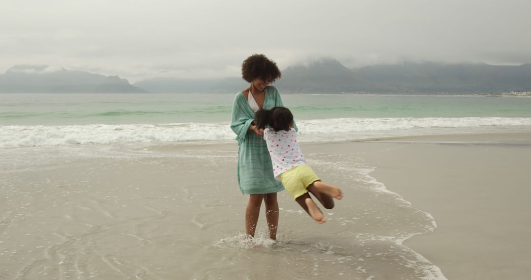 Smiling Mother Swinging Child on Beach - Free Images, Stock Photos and Pictures on Pikwizard.com