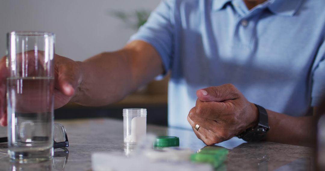 Senior biracial man with glass of water taking pills - Free Images, Stock Photos and Pictures on Pikwizard.com